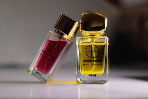 Close-Up Shot of Two Glass Perfume Bottles on White Surface
