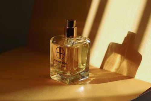 Close-Up Shot of Two Glass Perfume Bottles on Wooden Surface
