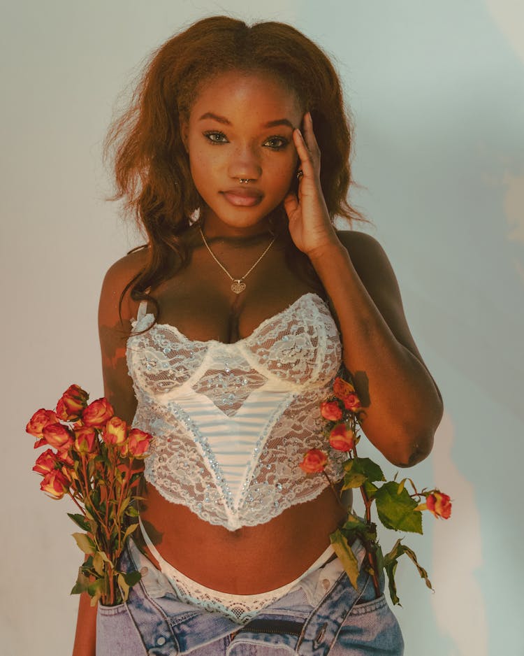 Young Woman In Crop Lacy Underwear And Jeans With Roses In Pockets