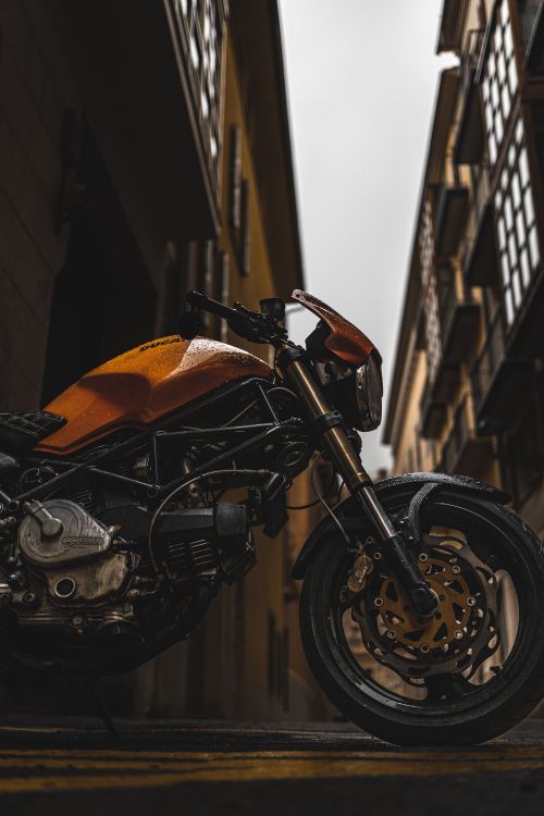 Free Dramatic side view of a motorcycle parked in a narrow alleyway between tall buildings. Stock Photo