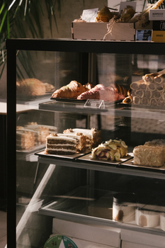 A variety of pastries elegantly displayed in a café cabinet, capturing warm, inviting tones.