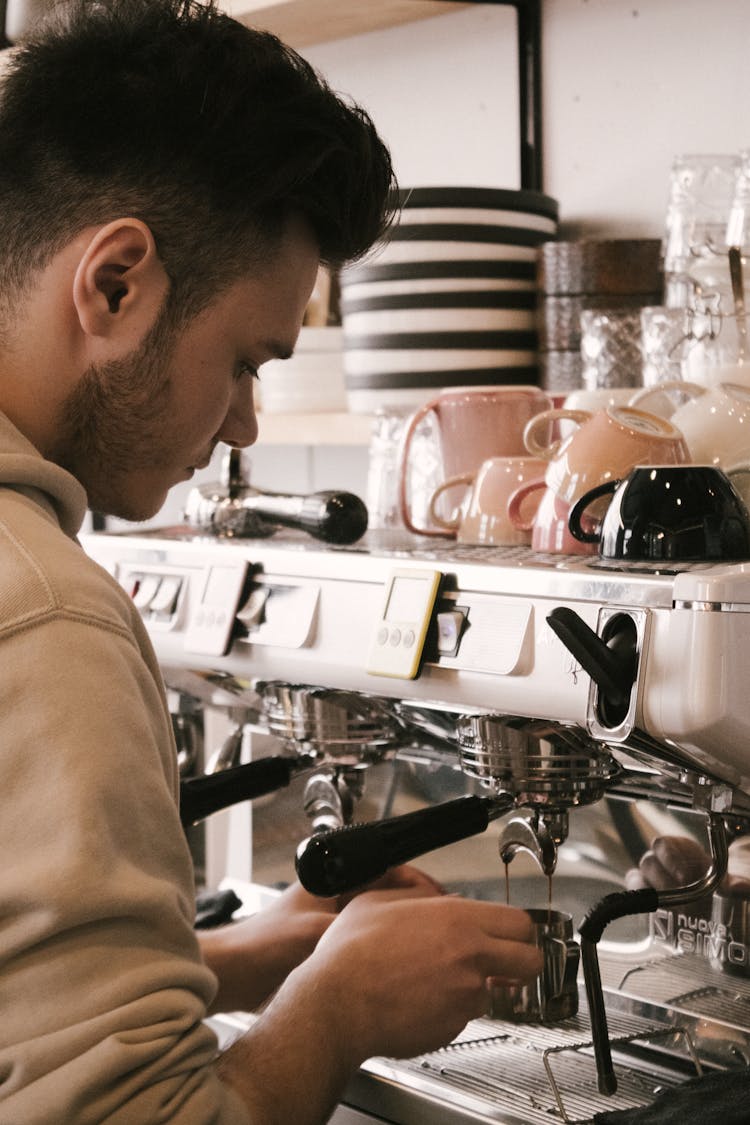 A Man In Brown Shirt Making Coffee On Espresso Machine