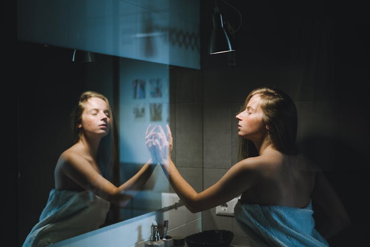 Woman Wrapped In Towel Touching Mirror In Bathroom 