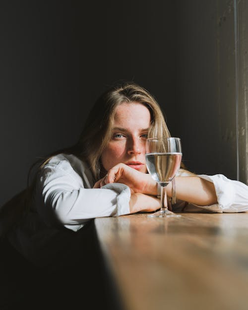 Free Woman Leaning on the Table and Looking at Glass of Wine  Stock Photo