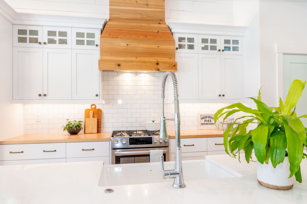Coastal kitchen with a marble island, white cabinets, and fresh greenery