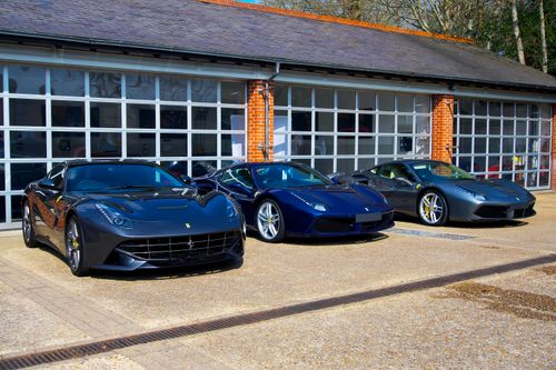 Free Three sleek luxury sports cars parked outside a modern garage in Lyndhurst. Stock Photo