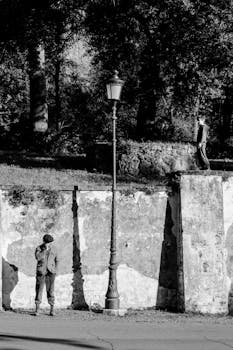Black and white image of men near street lamp, Rome setting.