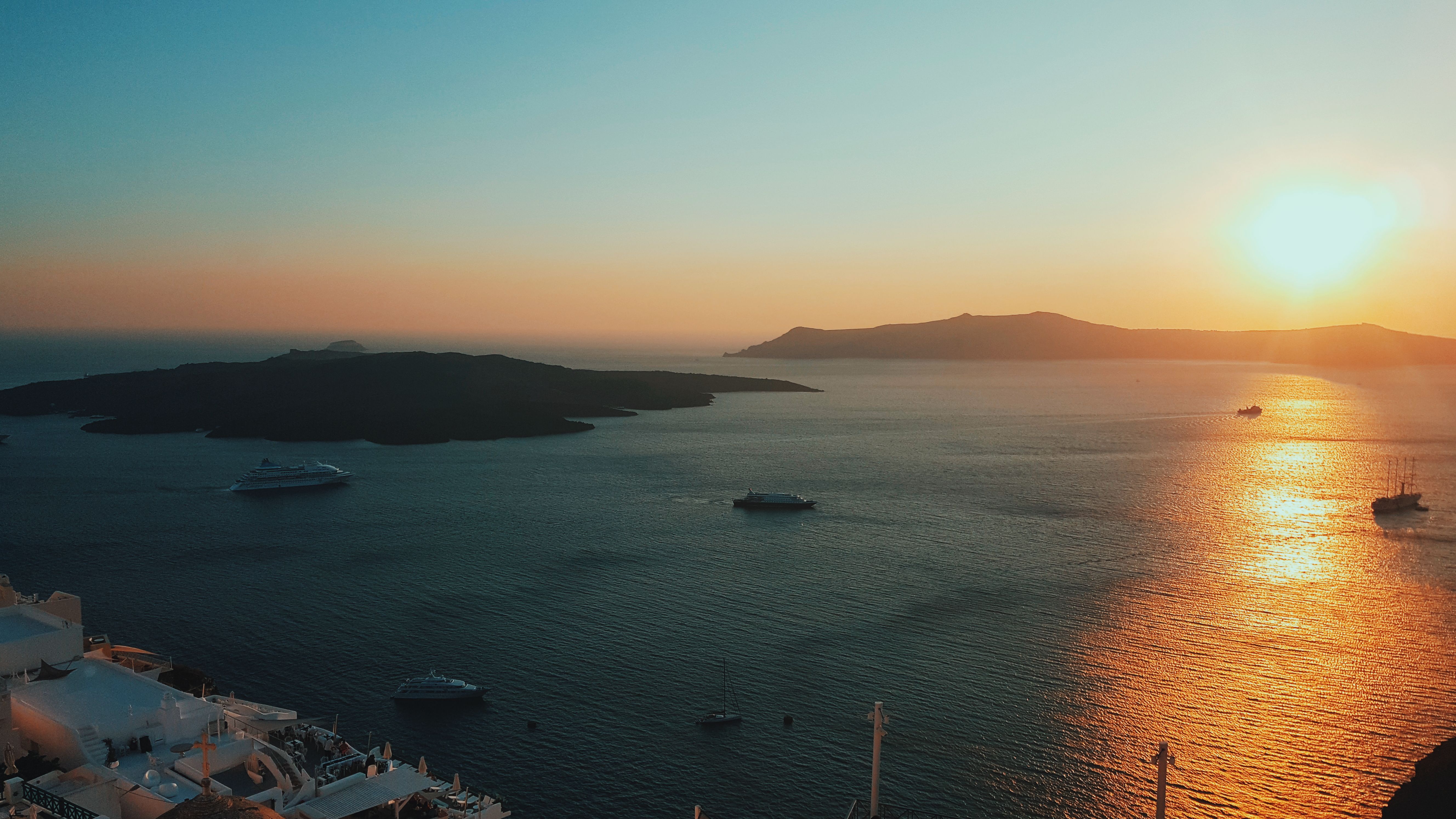 A serene sunset view over the Aegean Sea with boats and distant islands.