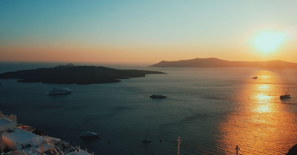 A serene sunset view over the Aegean Sea with boats and distant islands.