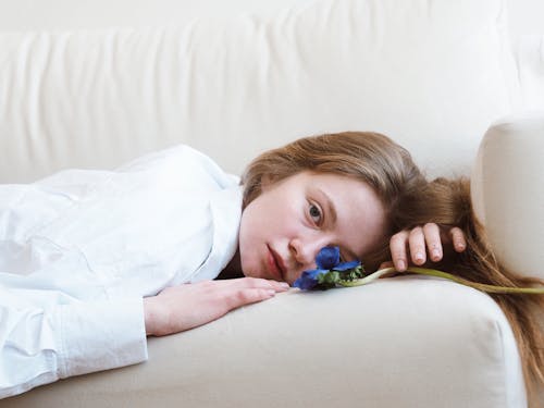 Free Sad Girl Lying on Sofa with Blue Flower Stock Photo
