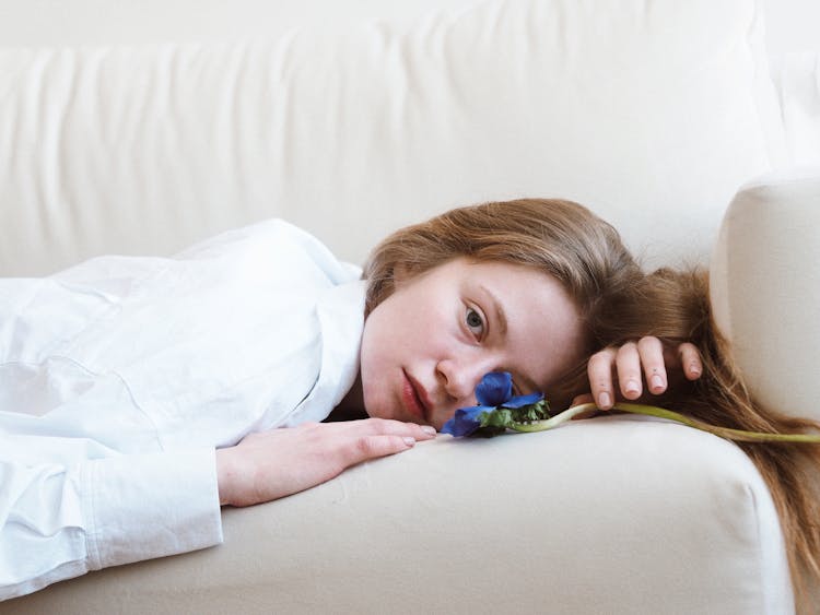 Sad Girl Lying On Sofa With Blue Flower