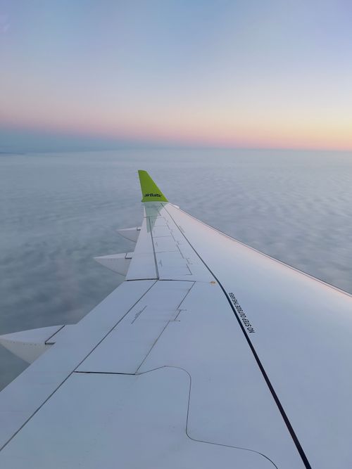 Free View of an airplane wing against a serene sunset sky over clouds. Stock Photo