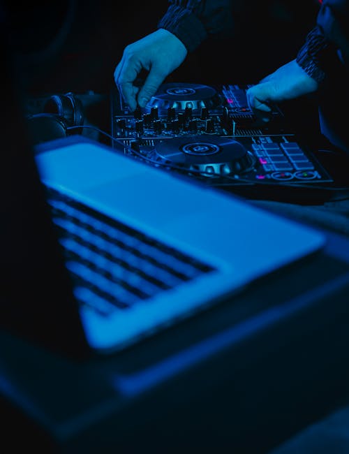 Hands of Person Operating Audio Mixer Near Laptop