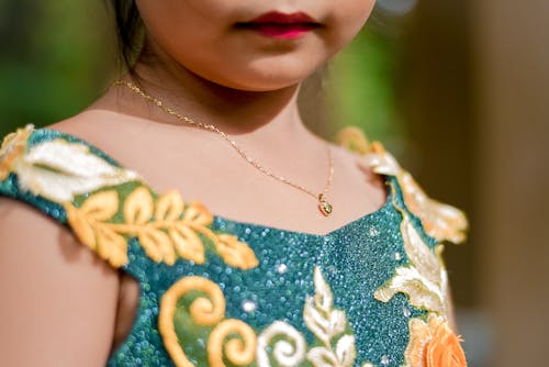 Close Up Photo of a Person Wearing Gold Necklace