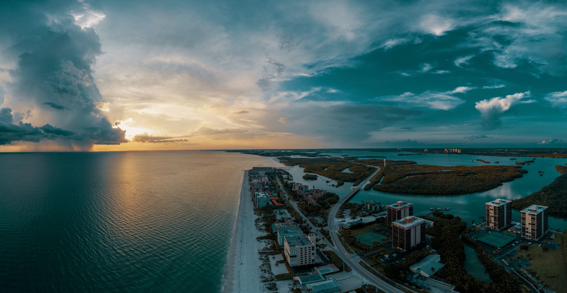 Stunning aerial view of Bonita Springs coastline during sunset with dramatic clouds.
