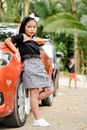 Girl in Black and White School Uniform Leaning on Red Car