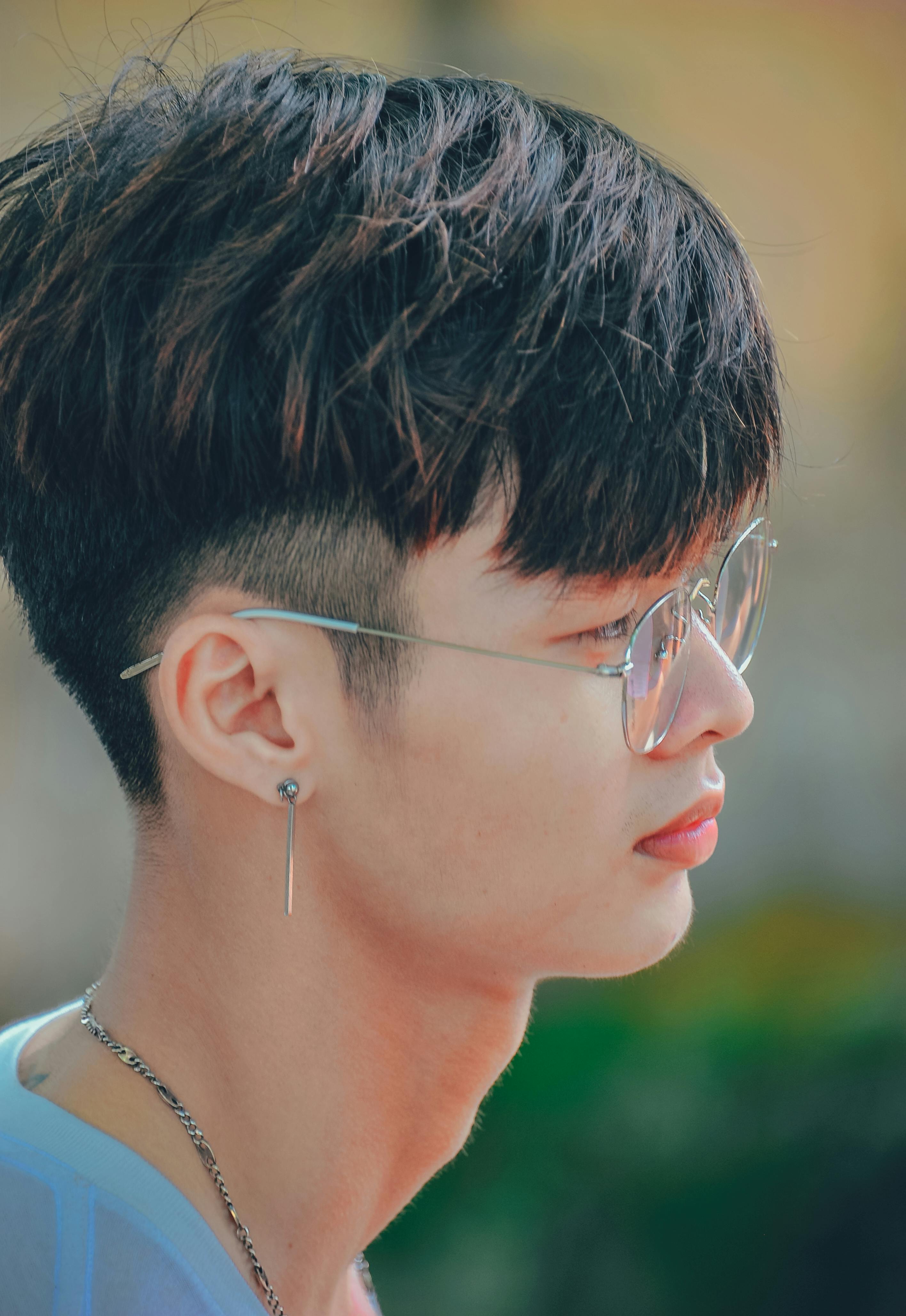 一个时髦年轻人的侧面，戴着眼镜和耳环