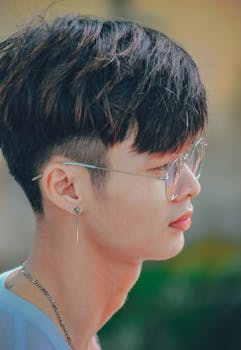 一个时髦年轻人的侧面，戴着眼镜和耳环