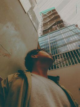 一个年轻人正凝视着一座现代摩天大楼，捕捉着城市的视角