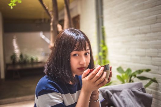 A young woman enjoying a cup of tea in a cozy indoor setting, capturing a moment of relaxation.
