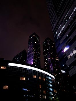 Illuminated skyscrapers in Moscow's urban landscape at night.