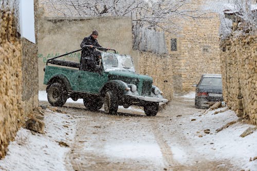 A Person Standing at the Back of a Vehicle while Snowing