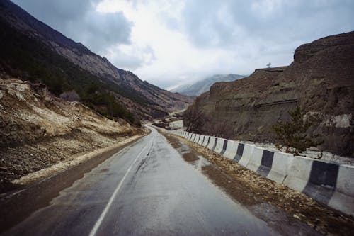 An Empty Road with Concrete Barriers Near the Mountains