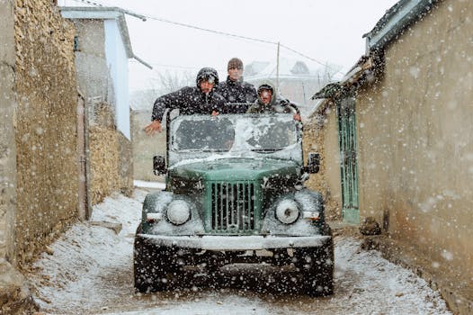 Three people drive a retro car through a narrow snowy street, creating a nostalgic winter atmosphere.
