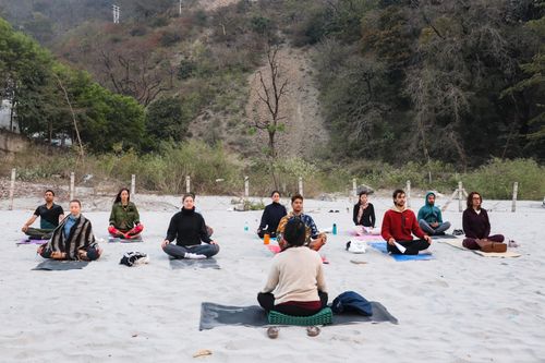 Free A group practicing meditation on a sandy beach in Rishikesh, India, promoting mindfulness and relaxation. Stock Photo