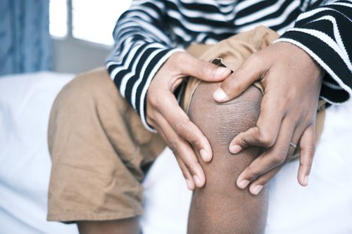 Free Close-up of a person holding their knee, highlighting skin texture and striped clothing. Stock Photo
