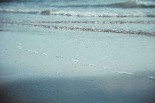 A close-up view of gentle waves lapping on a sandy beach, creating a serene coastal atmosphere.