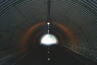 城市隧道幽暗，出口处灯光闪烁，营造出一种神秘而阴郁的氛围