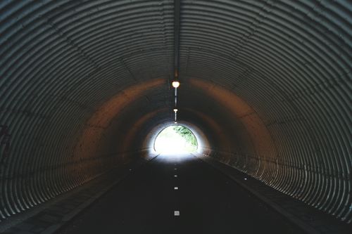 Free Dark urban tunnel with a light at its exit, creating a moody, mysterious atmosphere. Stock Photo