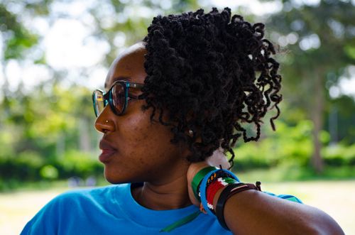 Free African woman with sunglasses and bracelets enjoying a sunny day outdoors. Stock Photo