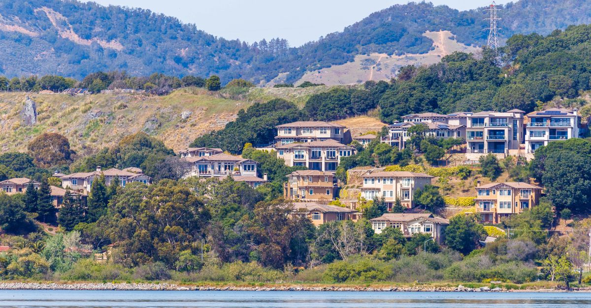 Panoramic view of luxury homes nestled on a picturesque hillside near the waterfront.