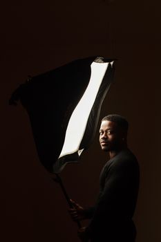 Fierce portrait of a man holding a softbox light in a studio setting, showcasing dramatic lighting.. pexels, fierce, portrait