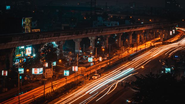 Long exposure capture of light trails on a Kolkata highway, showcasing urban nightlife and transportation.