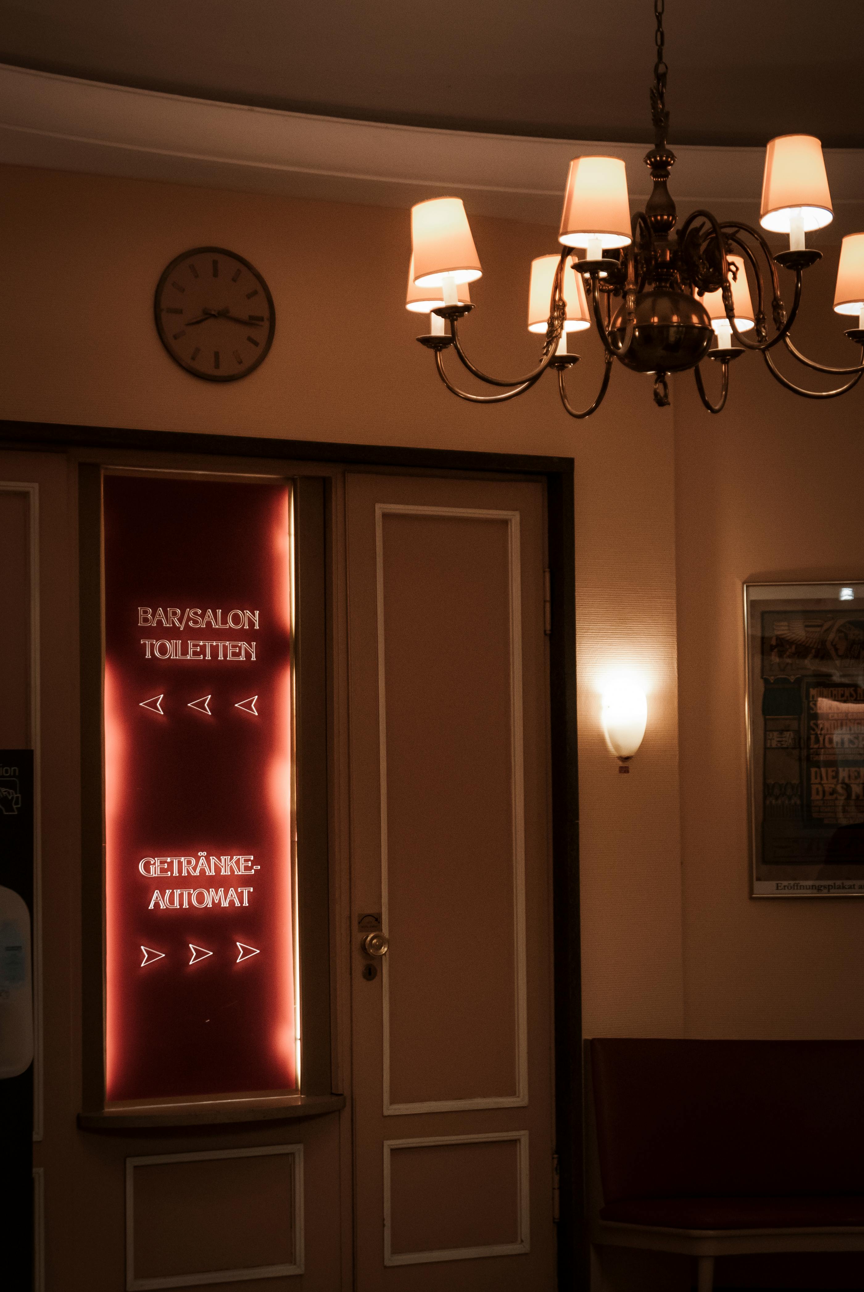 Warm-toned interior showcasing a chandelier and illuminated doorway signage.