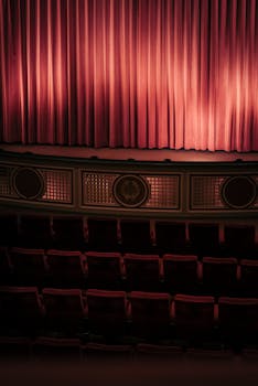 Elegant theater interior featuring red curtains and empty seats, perfect for performances.