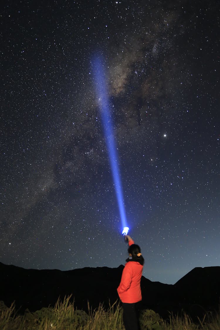 Woman Pointing A Flash Light To The Sky