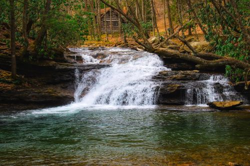 Free Picturesque waterfall cascading over rocky ledges in a serene forest environment. Stock Photo