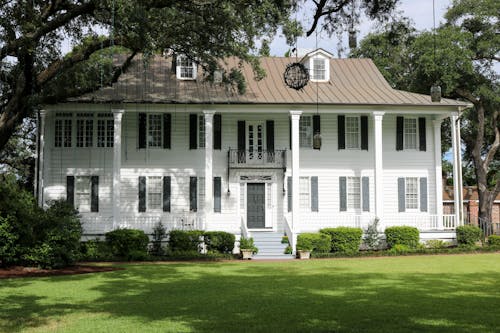 White Wooden House Beside Green Trees and Grass