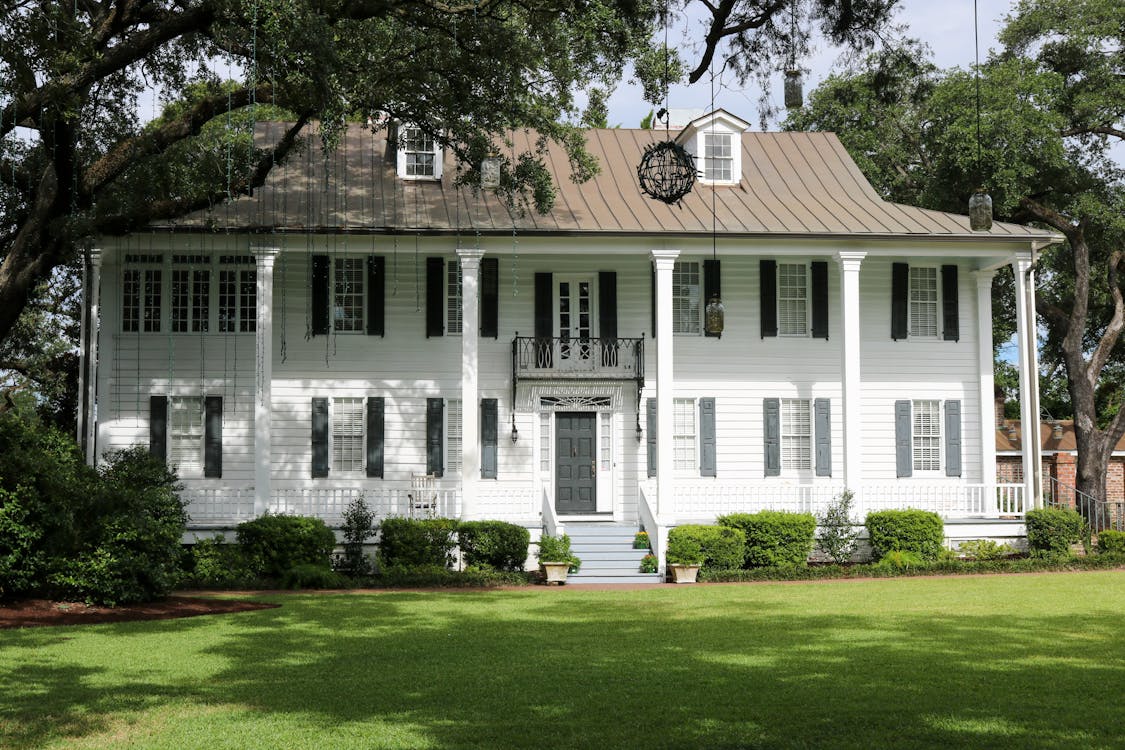 White Wooden House Beside Green Trees and Grass