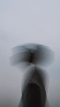 Abstract motion blur portrait of silhouetted figure with dynamic movement captured in a minimal setting.