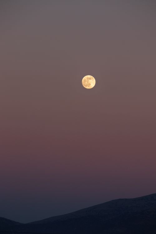 Free A stunning full moon illuminates the night sky over a serene mountainous terrain in Turkey. Stock Photo