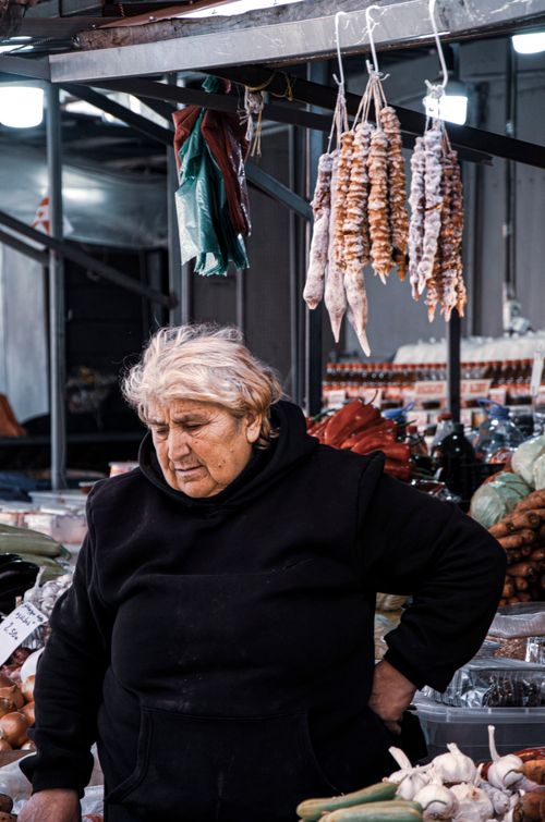 Free Senior woman selling produce at a bustling outdoor market. Stock Photo