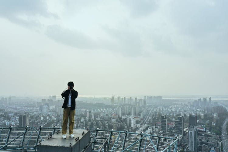 A Man Taking Photo While Standing Near The Edge Of A Building