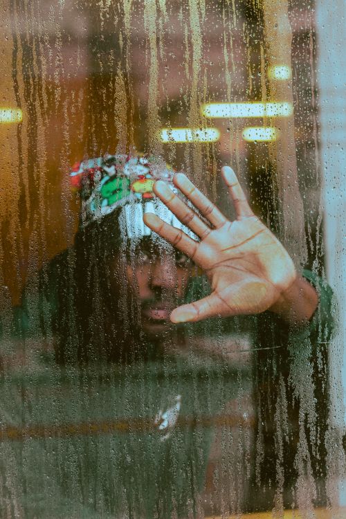 Free A man in Orlando, FL, touches a rain-soaked window, creating a mysterious and artistic scene. Stock Photo