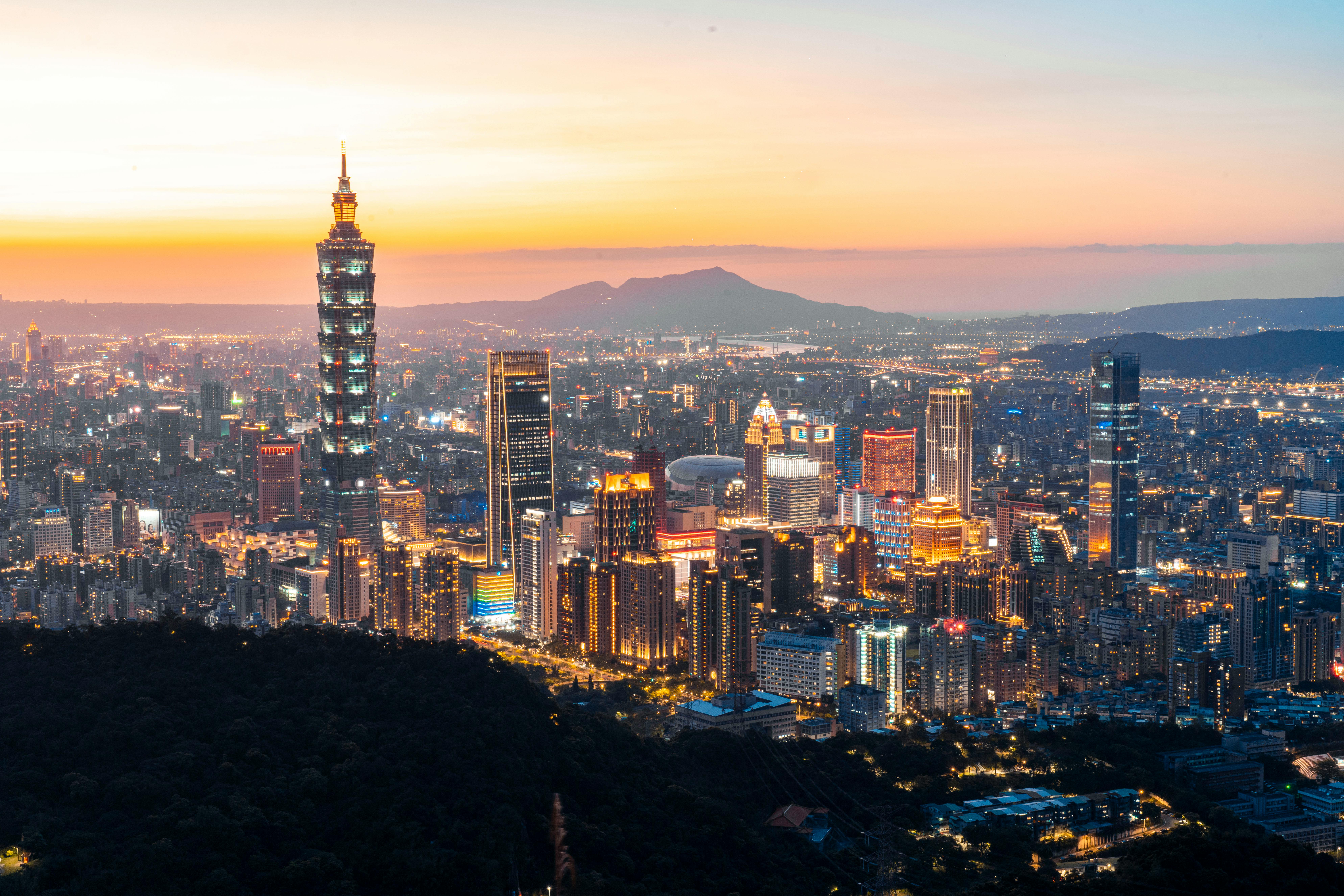 A breathtaking aerial view of Taipei city illuminated at dusk, featuring the iconic Taipei 101 tower.