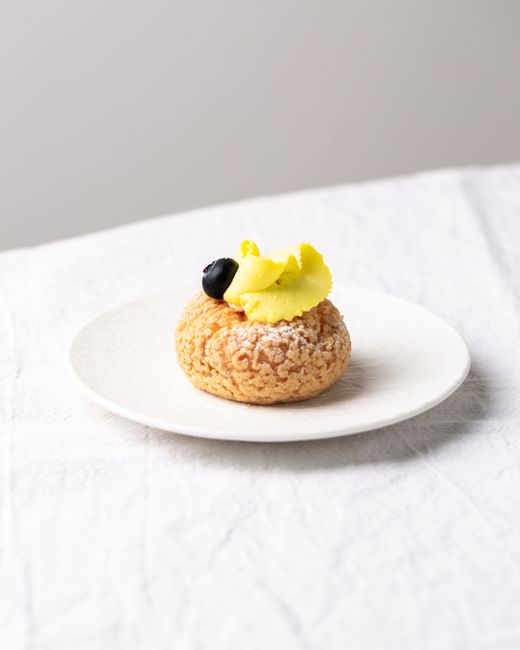 Gourmet cream puff on a plate with blueberry and lemon garnish, perfect for dessert lovers.